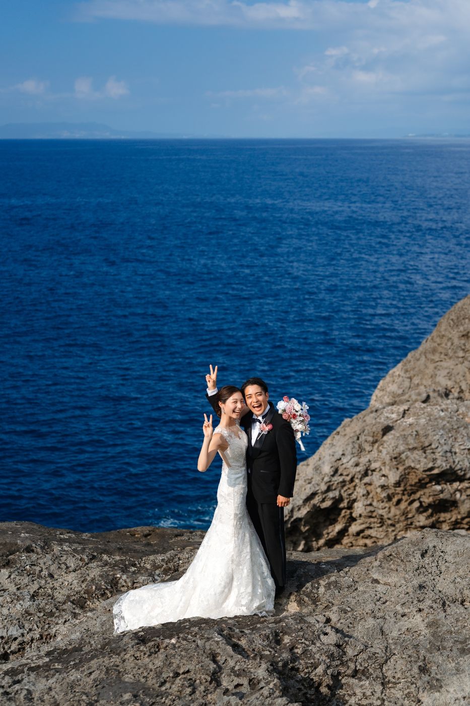 青い海を背にピースする新郎新婦